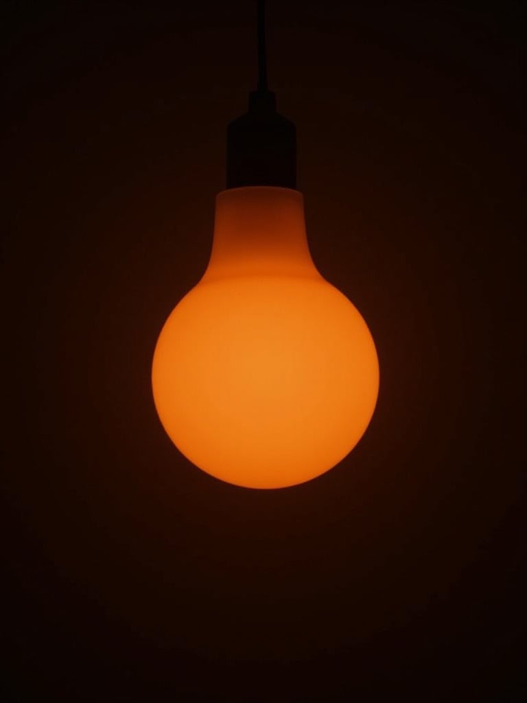 Image shows light from a sunset lamp. Warm glow against dark background. Simple and elegant lighting ambience.