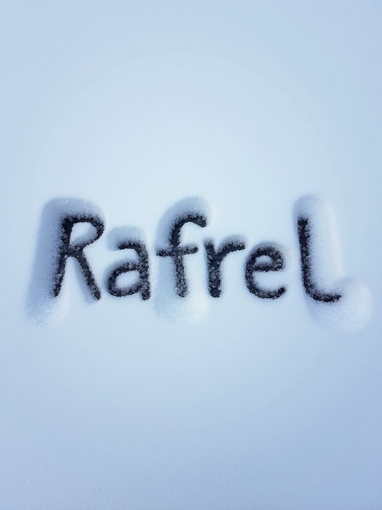 Name Rafrel written in snow. Shadow effect. White snow background. Black letters visible.