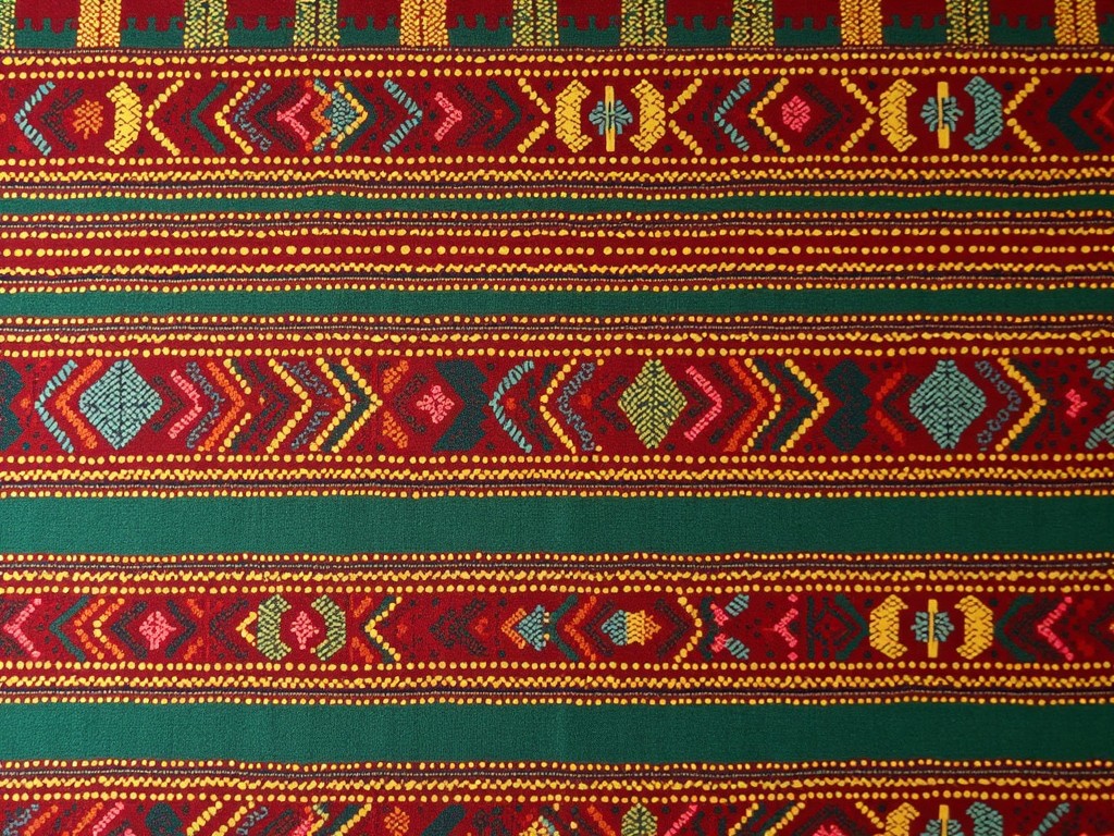 This image showcases a vibrant Ethiopian traditional cloth pattern. The fabric features intricate designs and a rich color palette, primarily consisting of red, green, yellow, and blue. Various geometric shapes and symbols are woven into the design, each reflecting the cultural significance of the region. The patterns are closely spaced, creating a rhythm that draws the eye along the fabric. This textile exemplifies the craftsmanship and artistry inherent in Ethiopian cultural textiles.