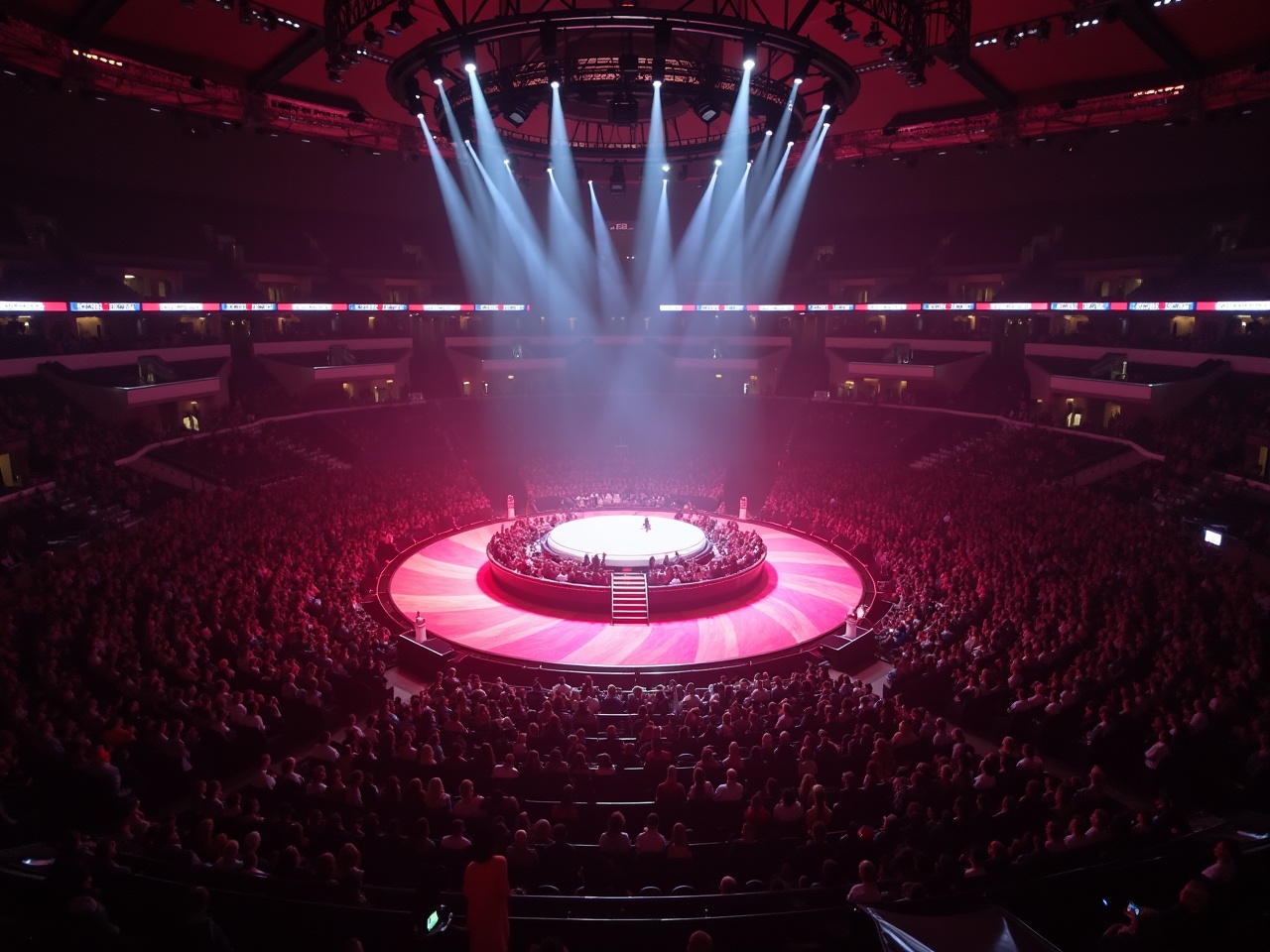 This image showcases a vibrant concert scene featuring a performance at Madison Square Garden. The stage is illuminated with dramatic lighting, creating an electrifying atmosphere. A large audience surrounds the stage, capturing the excitement of the event. The perspective offers a unique view from above, resembling a drone shot. The color palette highlights the intense reds and soft whites of the stage lighting, enhancing the overall mood of the concert.