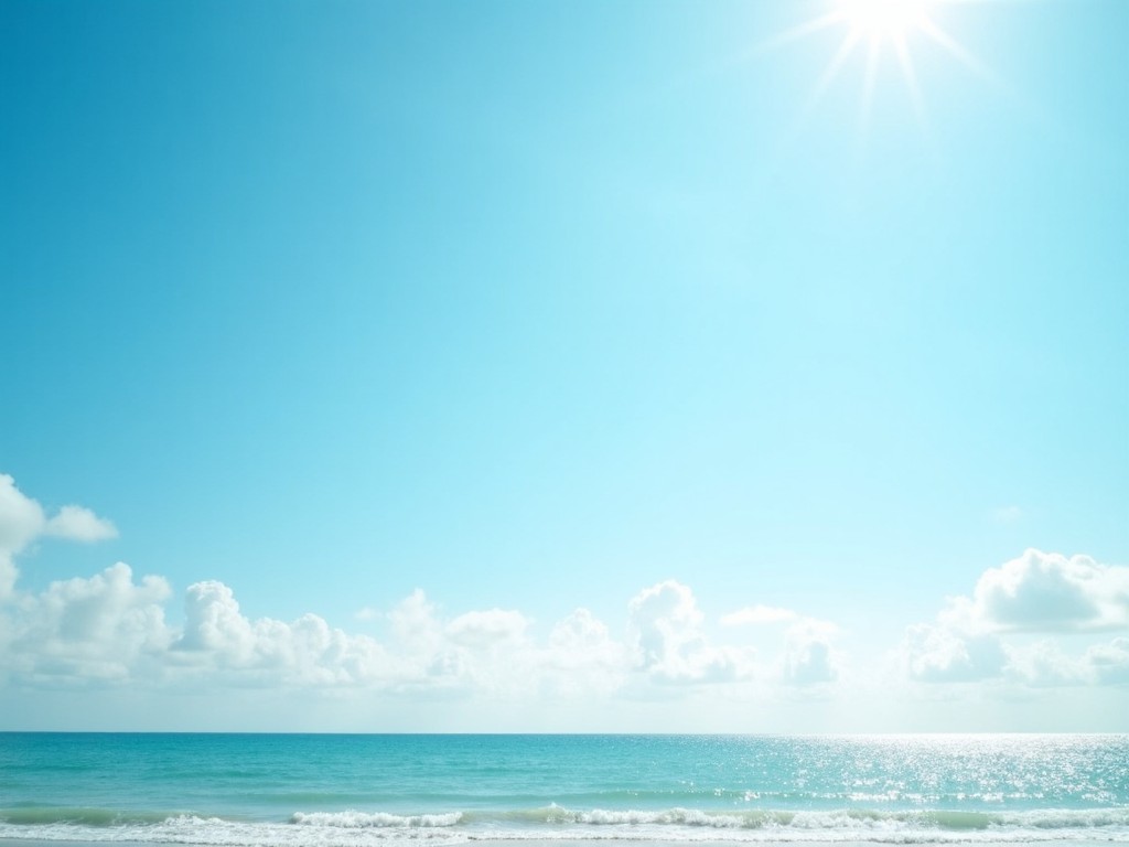 This image captures a serene view of the ocean against a clear sky. The light turquoise water reflects the bright sun shining above. Fluffy white clouds float gracefully across the vast blue expanse. This peaceful seascape evokes a sense of relaxation and calm. It is perfect for showcasing the beauty of nature and the joys of a beach destination.