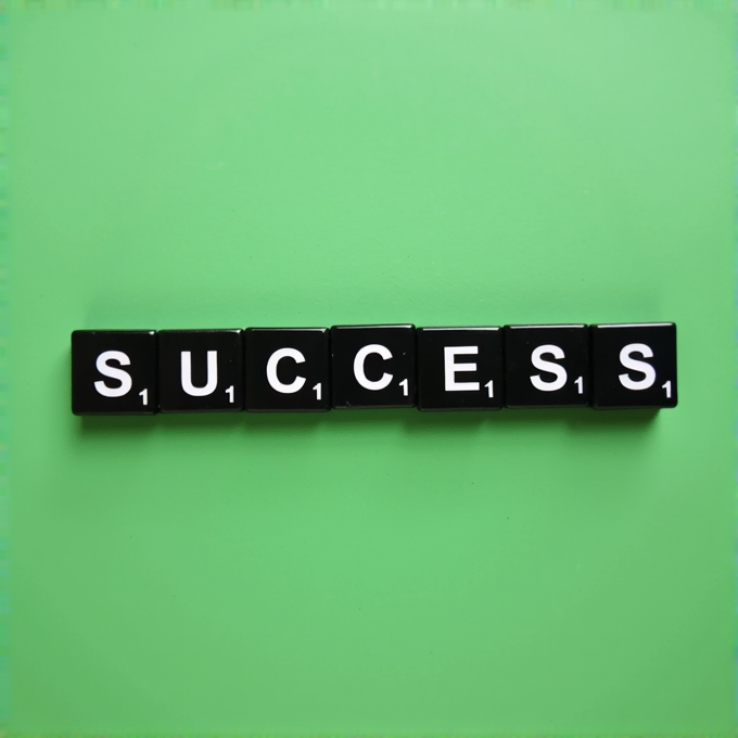 The word 'SUCCESS' is spelled out with black letter tiles on a bright green background.