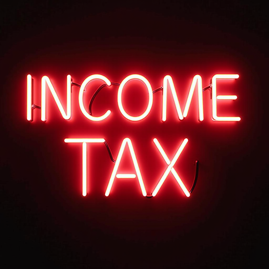 A vibrant neon sign displaying the words 'INCOME TAX' in bright red letters against a black background.