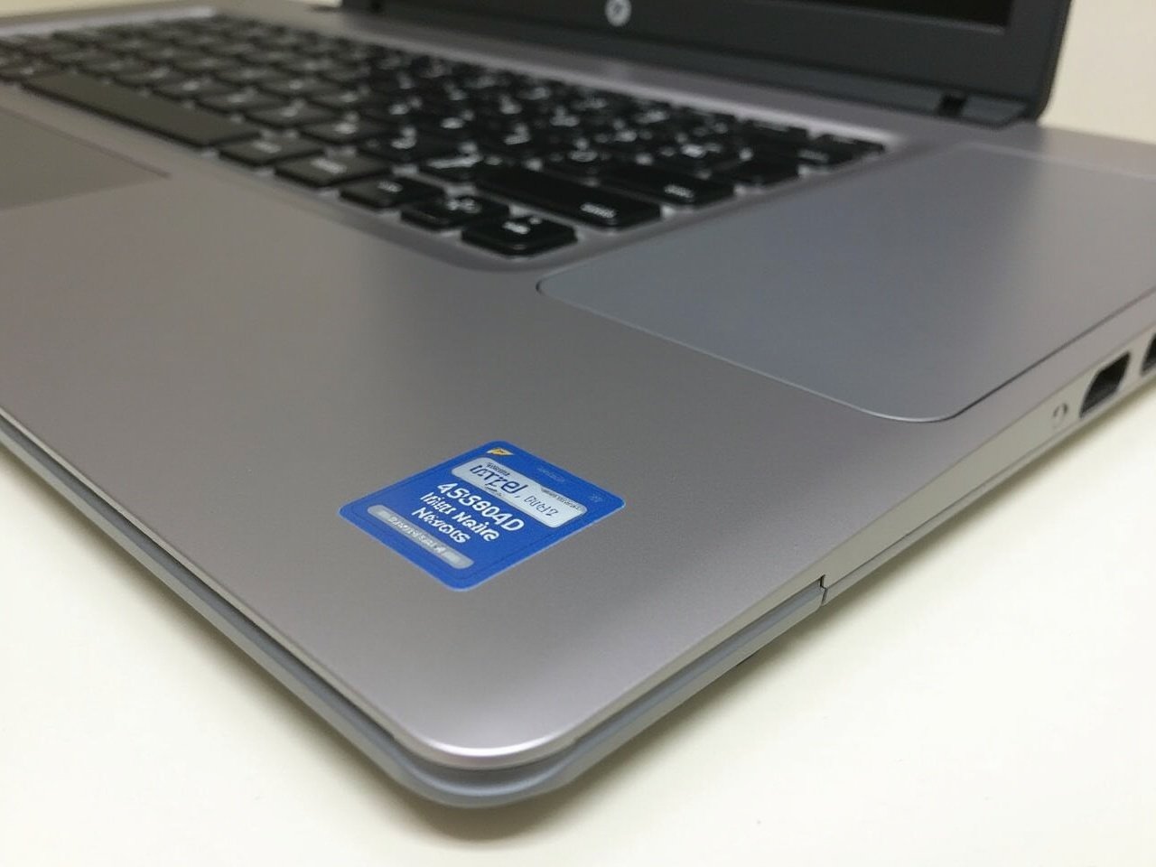 This image shows a close-up view of a sleek silver laptop, specifically from HP. The laptop is placed on a clean surface with the keyboard visible, showcasing modern keys. A blue sticker is prominently displayed, indicating it features an Intel processor. The image captures the elegant design typical of modern laptops. The lighting is bright and even, highlighting the device's metallic finish.