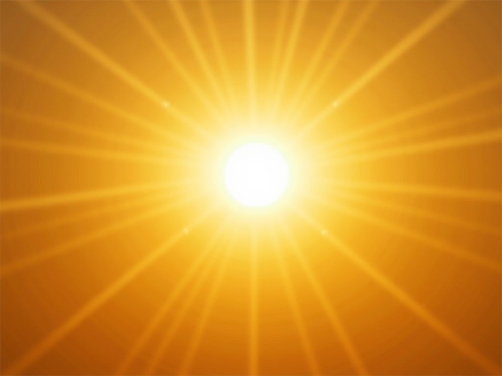 The image displays a radiant sunburst with a vibrant yellow and orange color palette. The center of the image is the brightest point, representing the sun, from which beams of light radiate outward. The symmetrical spread of light rays creates a striking visual effect, symbolizing warmth and energy.