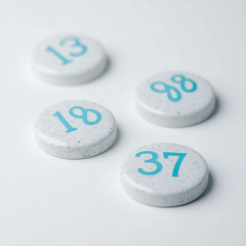 Four white discs with blue numbers are scattered on a smooth white surface.