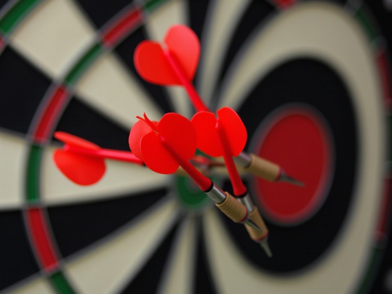 Four red darts are perfectly clustered in the bullseye of a dartboard, highlighting precision and accuracy. The dartboard features classic black and white segments, with red and green accents. This image captures a moment of perfect accuracy, ideal for showcasing skill in the game of darts. The vibrant red of the darts contrasts sharply with the black and white design of the board. It represents focus and strategic aim in a competitive context.