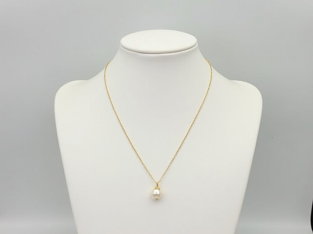 a pearl pendant necklace on a white bust display